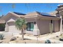 Beautiful home featuring desert landscaping, solar panels, a two-car garage, and a walkway to the entrance at 10694 E Firethorn Dr, Scottsdale, AZ 85255