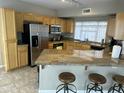 A well-lit kitchen featuring wood cabinets, stainless steel appliances, and a large island with bar seating at 1081 W 1St St # 18, Tempe, AZ 85281