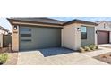 A modern home featuring a gray garage door and neutral stucco and siding, complemented by a brick driveway at 20332 W Sells Dr, Buckeye, AZ 85396