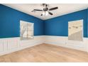 Well-lit bedroom with blue walls, white trim, hardwood floors and a ceiling fan at 5423 W Range Mule Dr, Phoenix, AZ 85083