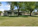 Ranch style house with mature trees and manicured lawn at 944 E Melody Dr, Gilbert, AZ 85234