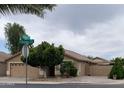 Inviting home featuring well-kept landscaping, a mature tree, and a visible street sign at the corner at 13031 W Surrey Ave, El Mirage, AZ 85335