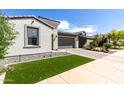 Well-maintained front yard with artificial turf, desert landscaping, and a paver driveway leading to a modern home at 17168 W Mountainair St, Surprise, AZ 85388