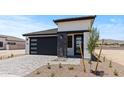 Charming home features a modern garage door, stone accents, and a drought-tolerant landscaped front yard at 20326 W Roma Ave, Buckeye, AZ 85396