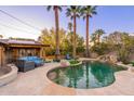 Lush backyard featuring a sparkling pool with waterfall, desert landscaping, tall palms, and outdoor seating area at 2712 E Mountain View Rd, Phoenix, AZ 85028