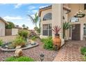 Lush front yard featuring a stone-lined pond with water feature, brick walkway, and mature desert landscaping at 5839 W Ironwood Dr, Glendale, AZ 85302