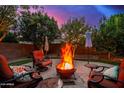 Landscaped backyard with a fire pit and comfortable seating, surrounded by mature trees and greenery at 9566 N 83Rd Dr, Peoria, AZ 85345