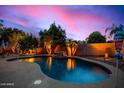 Backyard swimming pool with rock waterfall feature and lush landscaping, perfect for relaxing evenings at 9566 N 83Rd Dr, Peoria, AZ 85345