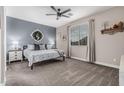 Comfortable bedroom with neutral paint, carpet flooring, a ceiling fan, and a large window providing natural light at 14419 W El Cortez Pl, Surprise, AZ 85387