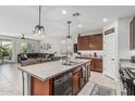 An open-concept kitchen and living area includes an island with a sink, brown cabinets, and tile floors at 14419 W El Cortez Pl, Surprise, AZ 85387