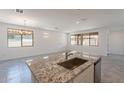 Open-concept kitchen featuring a large island with granite countertops, a sink, and natural light from the windows at 24184 W Gibson Ln, Buckeye, AZ 85326
