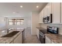 Well-lit kitchen with stainless steel appliances, white cabinets, granite countertops, and easy access to the living space at 24184 W Gibson Ln, Buckeye, AZ 85326