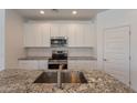 Modern kitchen featuring white cabinets, granite countertops, stainless steel appliances, and a stylish backsplash at 24184 W Gibson Ln, Buckeye, AZ 85326