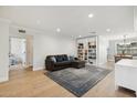 Cozy living room features hardwood floors, fresh paint, modern recessed lighting, and a large sofa at 2435 E Jensen St, Mesa, AZ 85213