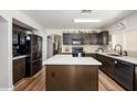 Modern kitchen featuring dark cabinets, a white island, stainless steel appliances and wood-look floors at 22783 W Cantilever St, Buckeye, AZ 85326