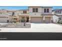 Two-story stucco home featuring a three-car garage, desert landscaping, and covered front porch at 30185 W Flower St, Buckeye, AZ 85396