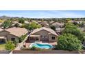 Aerial view of a backyard with a sparkling pool, covered patio, and lush landscaping at 4222 E Torrey Pines Ln, Chandler, AZ 85249