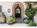 Inviting front entrance with a decorative tiled archway, lush landscaping, and stone walkway to the door at 4949 E Lincoln Dr # 11, Paradise Valley, AZ 85253