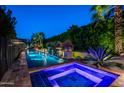 Tranquil pool and spa area with lush landscaping illuminated by ambient lighting at twilight at 6019 N 62Nd Pl, Paradise Valley, AZ 85253