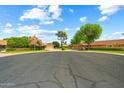 Wide street view of well-maintained homes with mature trees under a bright blue sky with scattered clouds at 19053 N Lakeforest Dr, Sun City, AZ 85373