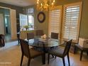 Bright dining room featuring a glass table, modern chairs, and natural light streaming through the window shutters at 20376 N Coronado Way, Surprise, AZ 85374