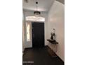 Elegant entryway with modern light fixture, stylish console table, and dark tile flooring at 21570 N Greenway Rd, Maricopa, AZ 85138