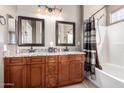 Bathroom featuring a double sink vanity with granite countertop, dark wood cabinets, and shower over tub combination at 3241 E Hampton Ln, Gilbert, AZ 85295