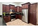 A well-equipped kitchen with stainless steel appliances, dark wood cabinets and granite counter tops and mosaic backsplash at 3284 E Sandy Way, Gilbert, AZ 85297