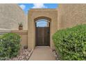 Stucco wall with an arched gate and wrought iron door, framed by lush green bushes and desert landscaping at 4545 E Wescott Dr, Phoenix, AZ 85050