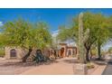 Inviting single-story home highlighting desert landscaping with mature trees and well-maintained surroundings at 4706 E Rancho Caliente Dr, Cave Creek, AZ 85331