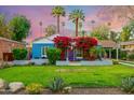 Inviting blue home featuring lush landscaping and bougainvillea around the front door, set against a stunning sky at 512 W Roma Ave, Phoenix, AZ 85013
