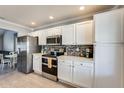 Modern kitchen features white cabinets, stainless steel appliances, and mosaic tile backsplash at 6938 W Wescott Dr, Glendale, AZ 85308