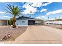 Inviting single-story home with covered parking, mature palm trees, and low-maintenance desert landscaping at 7302 E Baseline Rd, Mesa, AZ 85209