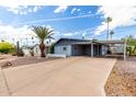 Charming single-story home with covered parking, mature palm trees, and low-maintenance desert landscaping at 7302 E Baseline Rd, Mesa, AZ 85209