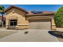 Tan home features a two-car garage, awning over a window, desert landscaping and solar panels at 11664 W Eagle Ct, Surprise, AZ 85378