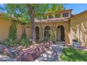 Inviting front entrance with stone accents, mature trees and flowering vines cascading over the arched porch at 1308 E Rosemonte Dr, Phoenix, AZ 85024