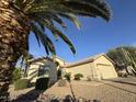 Inviting home with lush desert landscaping, mature palm trees, and a well-maintained front yard at 14878 W Verde Ln, Goodyear, AZ 85395