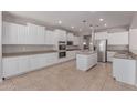 Spacious kitchen featuring white cabinetry, stainless steel appliances, and a large island with tile floors at 18868 E Canary Way, Queen Creek, AZ 85142