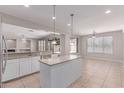 Bright kitchen with an island, stainless steel sink, modern pendant lighting and tan-colored tile floors at 18868 E Canary Way, Queen Creek, AZ 85142
