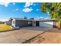 Low angle of exterior showing dark gray siding and white trim, large driveway, and detached two-car garage at 4518 W Rose Ln, Glendale, AZ 85301