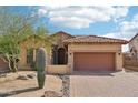 Lovely tan home features a two car garage, decorative stone, and low maintenance desert landscaping at 6937 E Sierra Morena Cir, Mesa, AZ 85207