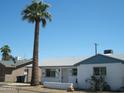 Single-story home with white exterior, blue trim, and a tall palm tree at 7821 W Clarendon Ave, Phoenix, AZ 85033