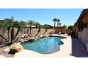 Resort style backyard featuring a pool with rock waterfall, lush landscaping, and a lounge chair at 10628 W Country Club Trl, Peoria, AZ 85383