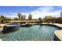 Resort-style pool and spa with waterfall feature, surrounded by lush landscaping and desert views at 1141 W Stephanie Ln, San Tan Valley, AZ 85143