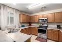 Functional kitchen with oak cabinets, stainless steel appliances, and a view of a window for natural light at 11841 W Laurel Ln, El Mirage, AZ 85335