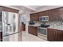 Well-equipped kitchen with stainless steel appliances, mosaic backsplash, and dark wood cabinetry at 1560 E Flint St, Chandler, AZ 85225