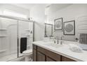 Bright bathroom featuring a vanity with dark wood cabinetry, a white countertop, and glass-enclosed shower at 17749 W Onyx Ave, Waddell, AZ 85355