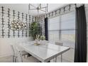 Bright dining room with a modern chandelier, white marble-topped table and designer wallpaper at 17755 W Onyx Ave, Waddell, AZ 85355