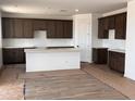 Spacious kitchen featuring dark wood cabinets, a center island, white countertops, and stainless steel appliances at 22368 W Monona Ln, Surprise, AZ 85387