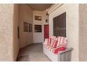 Cozy covered porch with a comfortable cushioned bench, perfect for enjoying the outdoors and a red front door at 2926 N 149Th Dr, Goodyear, AZ 85395